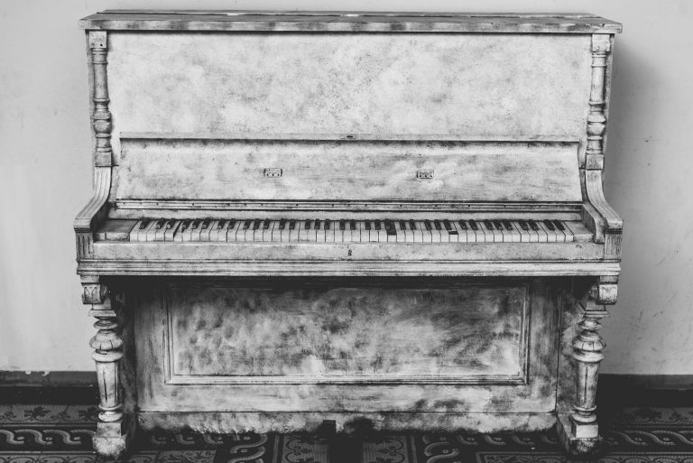 A beautifully aged, antique upright piano in black and white photography. Perfect for vintage decor themes.